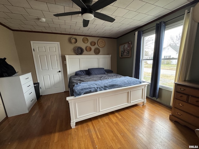 bedroom with multiple windows, light hardwood / wood-style floors, ceiling fan, and crown molding