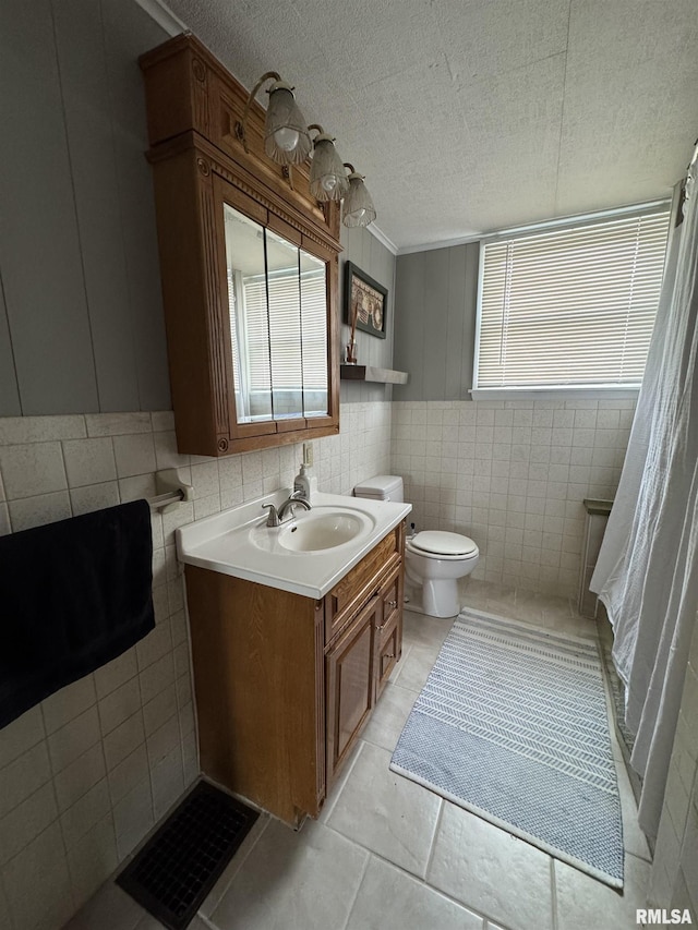 bathroom with tile patterned flooring, vanity, toilet, and tile walls