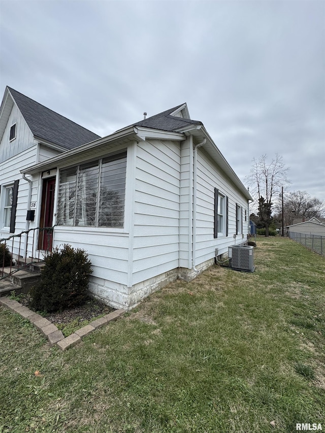 view of side of home with a lawn and central AC unit