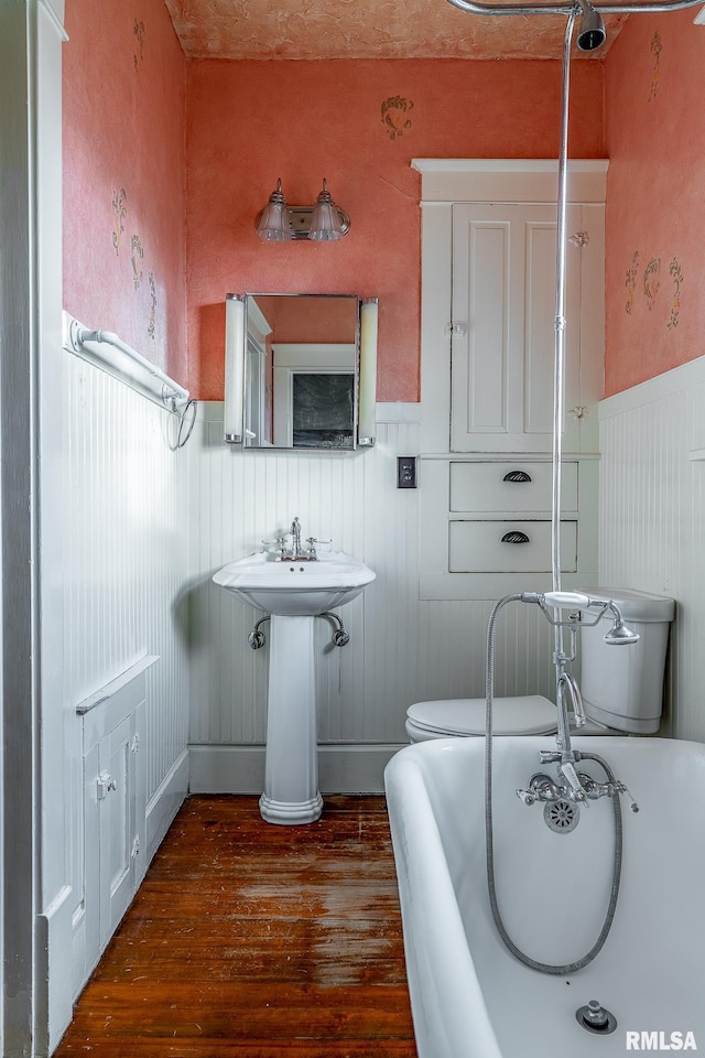 bathroom featuring a washtub, wood-type flooring, and toilet