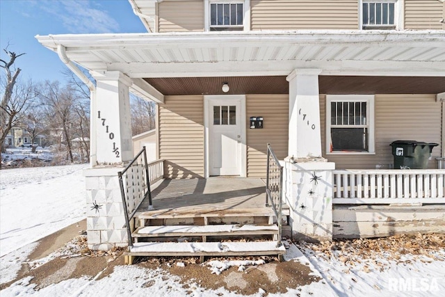 snow covered property entrance featuring covered porch