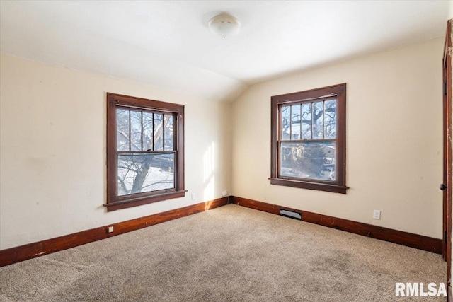 carpeted spare room with vaulted ceiling