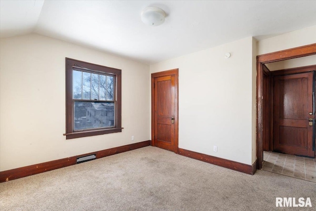 spare room featuring light carpet and vaulted ceiling