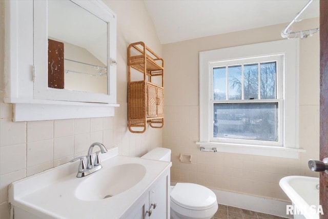 bathroom with vanity, toilet, lofted ceiling, and tile walls