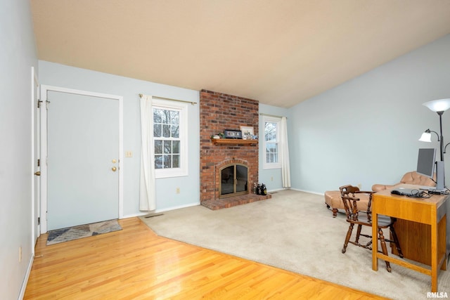 living room with wood-type flooring, a brick fireplace, and lofted ceiling