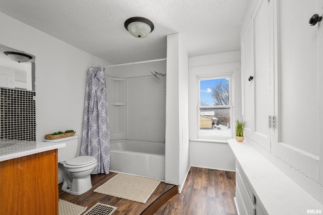 full bathroom with vanity, hardwood / wood-style flooring, toilet, a textured ceiling, and shower / tub combo