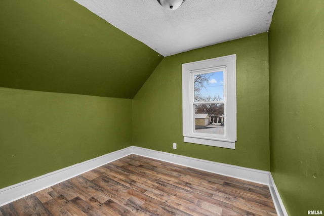 additional living space featuring lofted ceiling, wood-type flooring, and a textured ceiling