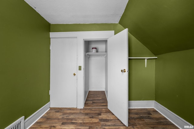 interior space with lofted ceiling, dark hardwood / wood-style floors, and a textured ceiling