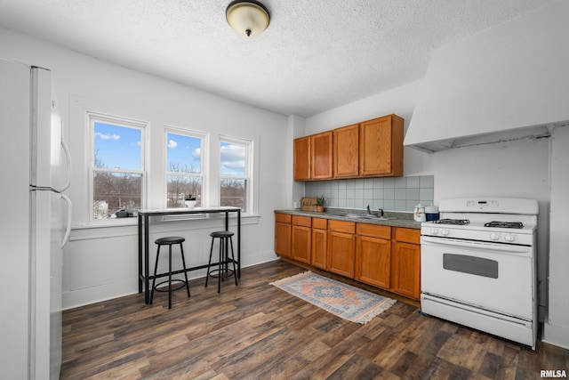 kitchen with backsplash, a textured ceiling, white appliances, sink, and dark hardwood / wood-style floors