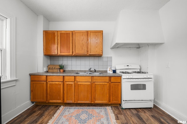 kitchen featuring white gas range, sink, dark hardwood / wood-style floors, a textured ceiling, and decorative backsplash