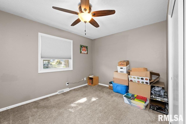 interior space with a textured ceiling, carpet floors, and ceiling fan