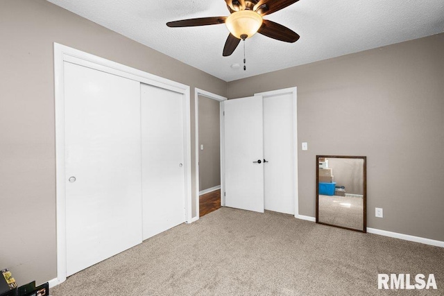 unfurnished bedroom with ceiling fan, a closet, light colored carpet, and a textured ceiling