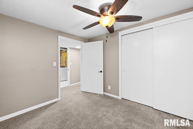 unfurnished bedroom featuring ceiling fan, a textured ceiling, washer / dryer, light carpet, and a closet