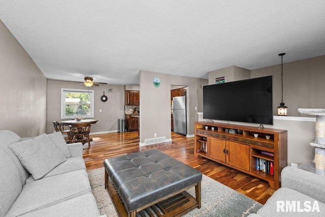 living room with a textured ceiling, hardwood / wood-style flooring, and ceiling fan