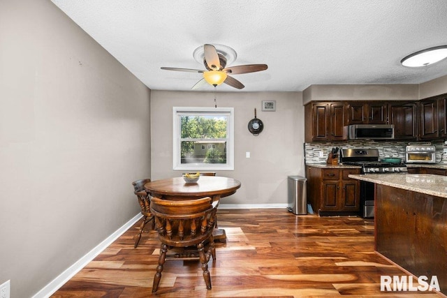 kitchen featuring backsplash, dark brown cabinetry, dark wood-type flooring, and appliances with stainless steel finishes