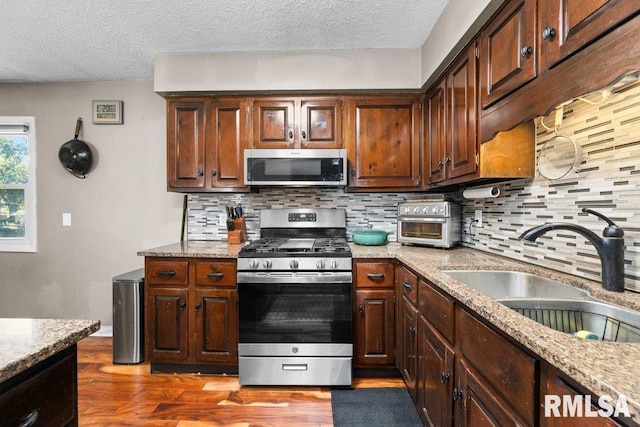 kitchen featuring tasteful backsplash, sink, stainless steel appliances, and a textured ceiling