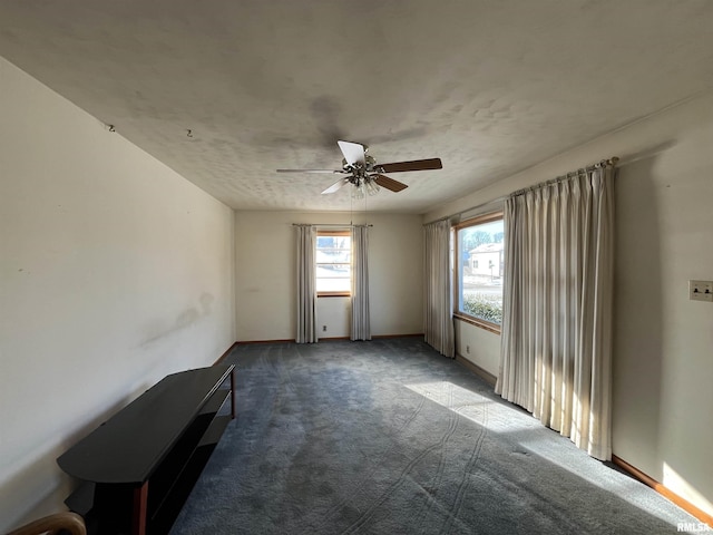 unfurnished room with ceiling fan and dark carpet