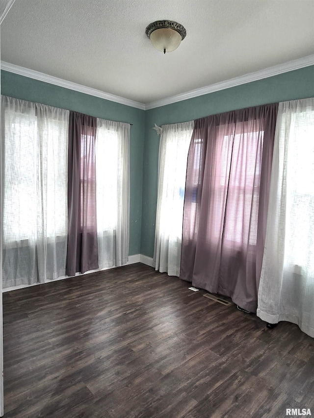 empty room with dark wood-type flooring, ornamental molding, and a textured ceiling