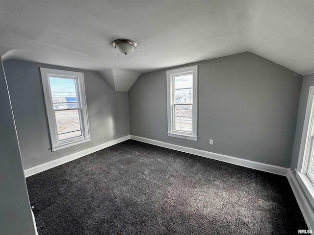 additional living space with a wealth of natural light, dark carpet, and vaulted ceiling