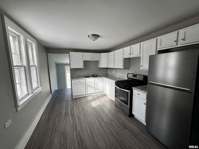 kitchen featuring dark wood-type flooring, sink, stone countertops, white cabinetry, and stainless steel appliances