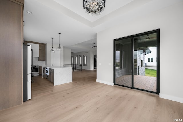 interior space featuring ceiling fan with notable chandelier and light hardwood / wood-style flooring