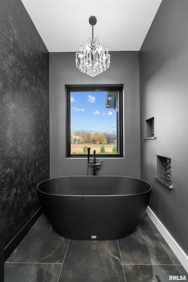 bathroom featuring a notable chandelier and a tub to relax in