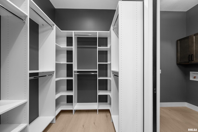 walk in closet with light hardwood / wood-style flooring