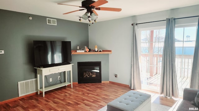 living room featuring hardwood / wood-style floors, ceiling fan, and a water view