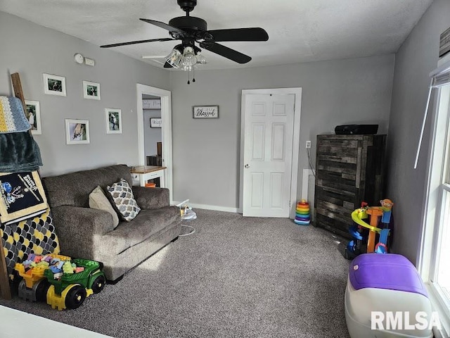 carpeted living room featuring ceiling fan and a textured ceiling