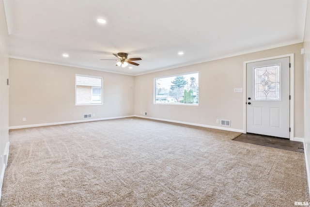 interior space featuring ceiling fan, plenty of natural light, and ornamental molding