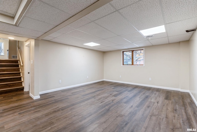 basement with a drop ceiling and dark hardwood / wood-style flooring