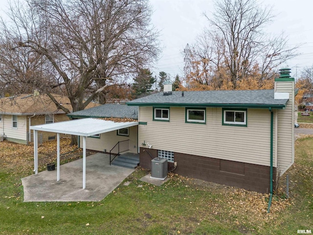 back of property with central AC unit, a patio area, and a yard