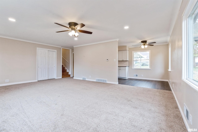 unfurnished living room featuring ceiling fan, dark carpet, and crown molding