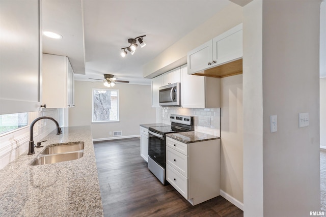 kitchen featuring white cabinets, sink, ceiling fan, appliances with stainless steel finishes, and light stone counters