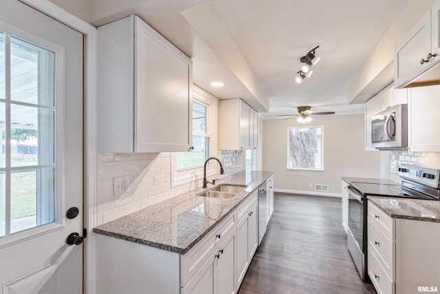 kitchen with dark stone counters, white cabinets, sink, tasteful backsplash, and stainless steel appliances