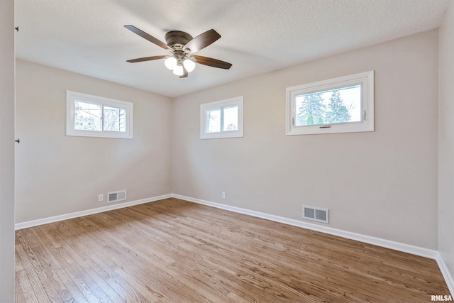 empty room with ceiling fan, a textured ceiling, and light wood-type flooring