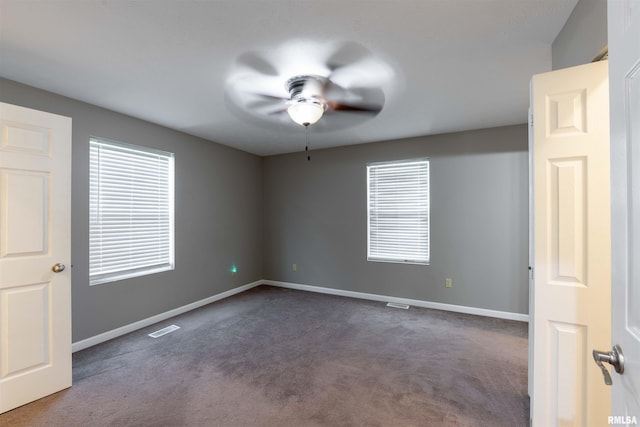 empty room with dark colored carpet and ceiling fan