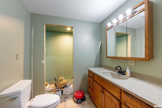 bathroom with tile patterned flooring, vanity, toilet, and a textured ceiling