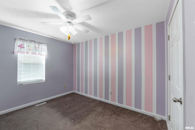 empty room with ceiling fan and dark colored carpet