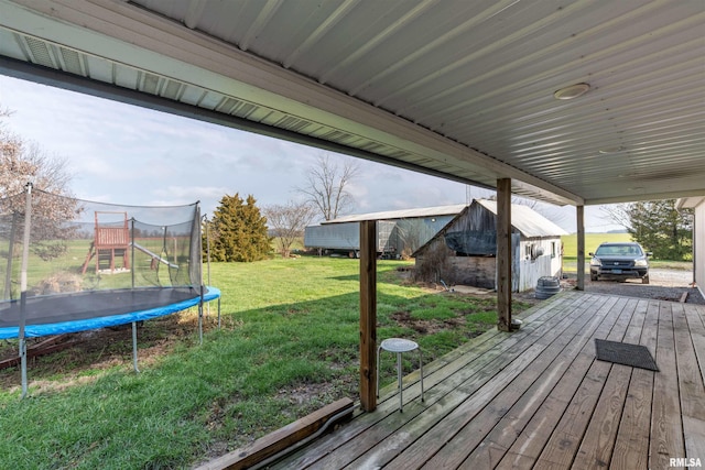 deck with a yard, an outdoor structure, and a trampoline