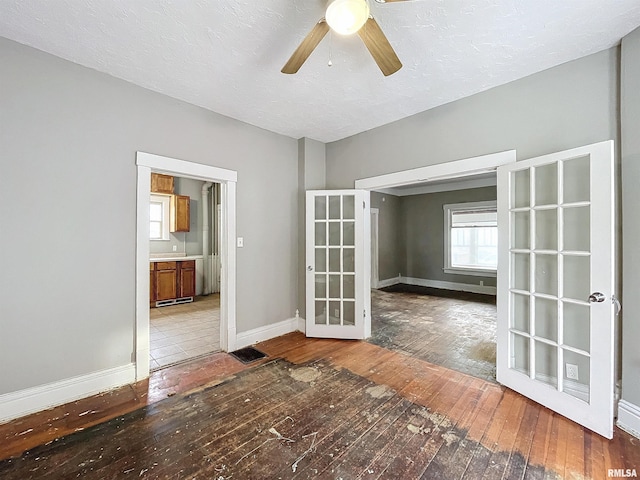 unfurnished room featuring ceiling fan, wood-type flooring, a textured ceiling, and french doors