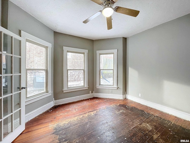 empty room featuring plenty of natural light, ceiling fan, dark hardwood / wood-style flooring, and a textured ceiling