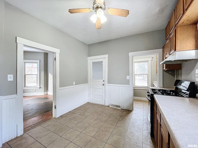 kitchen with black stove, plenty of natural light, ceiling fan, and light tile patterned flooring