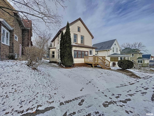 snow covered rear of property with a wooden deck