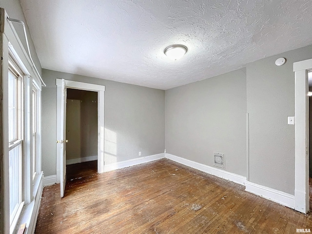 empty room featuring wood-type flooring and a textured ceiling