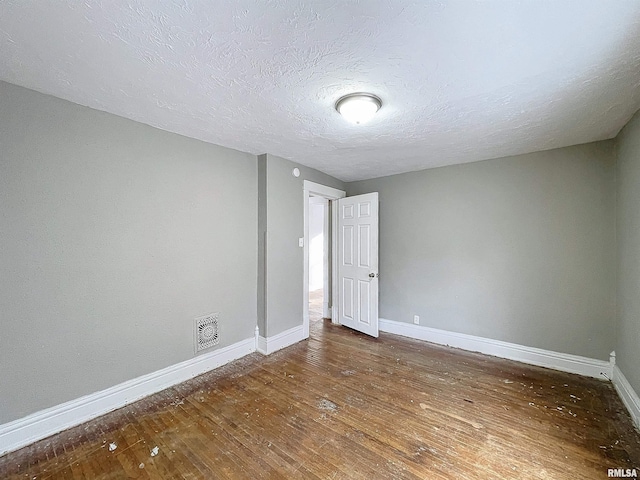 spare room with dark wood-type flooring and a textured ceiling