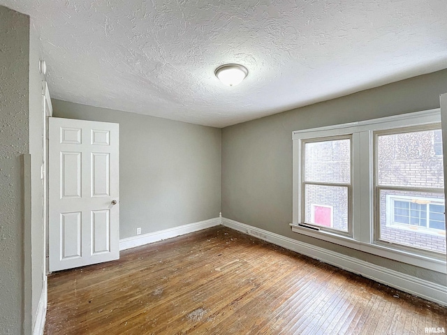 unfurnished room with hardwood / wood-style floors and a textured ceiling