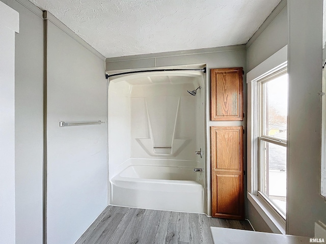 bathroom featuring a healthy amount of sunlight, wood-type flooring, a textured ceiling, and bathtub / shower combination