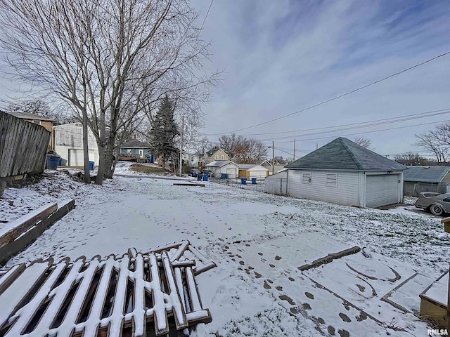 snowy yard featuring an outbuilding and a garage