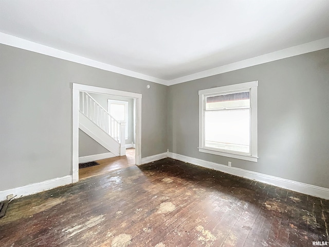 unfurnished room featuring ornamental molding and dark wood-type flooring